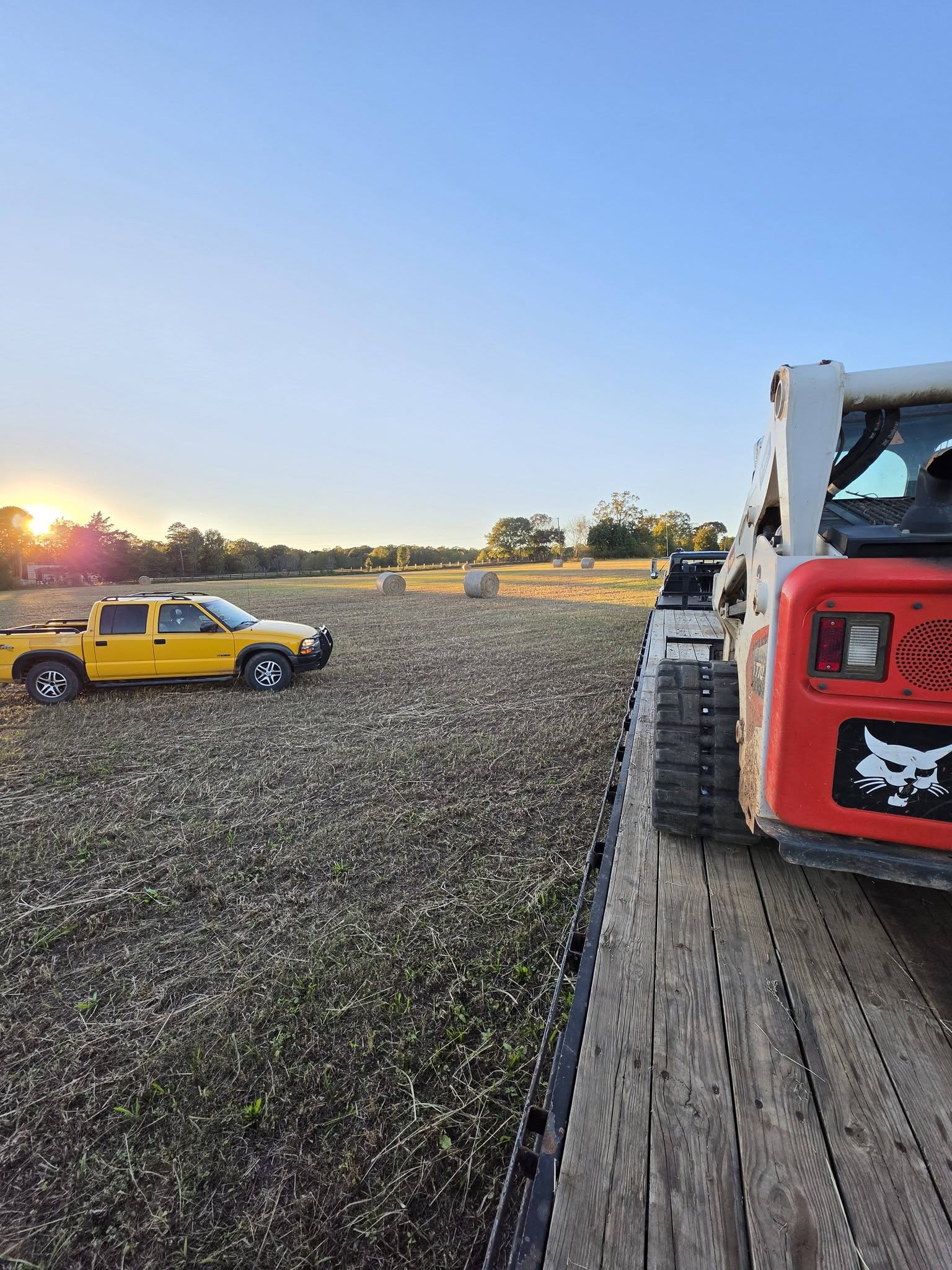 Compact track loader and trailer at the hay field